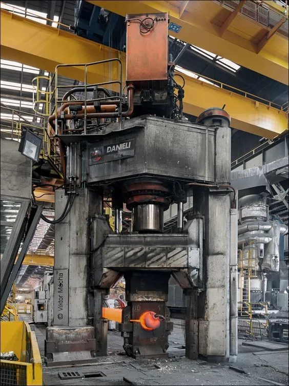 Prensa de forja industrial con una pieza incandescente.