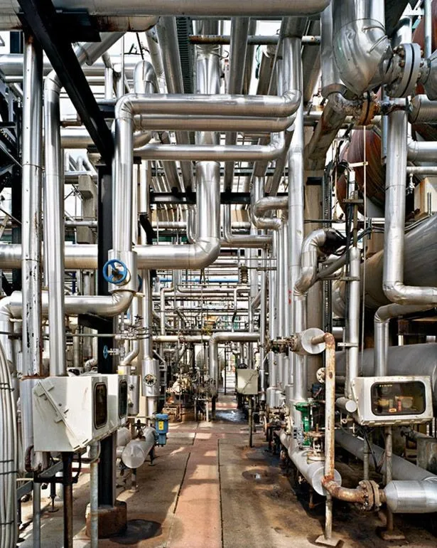 Corredor de tuberías y válvulas en una planta industrial.